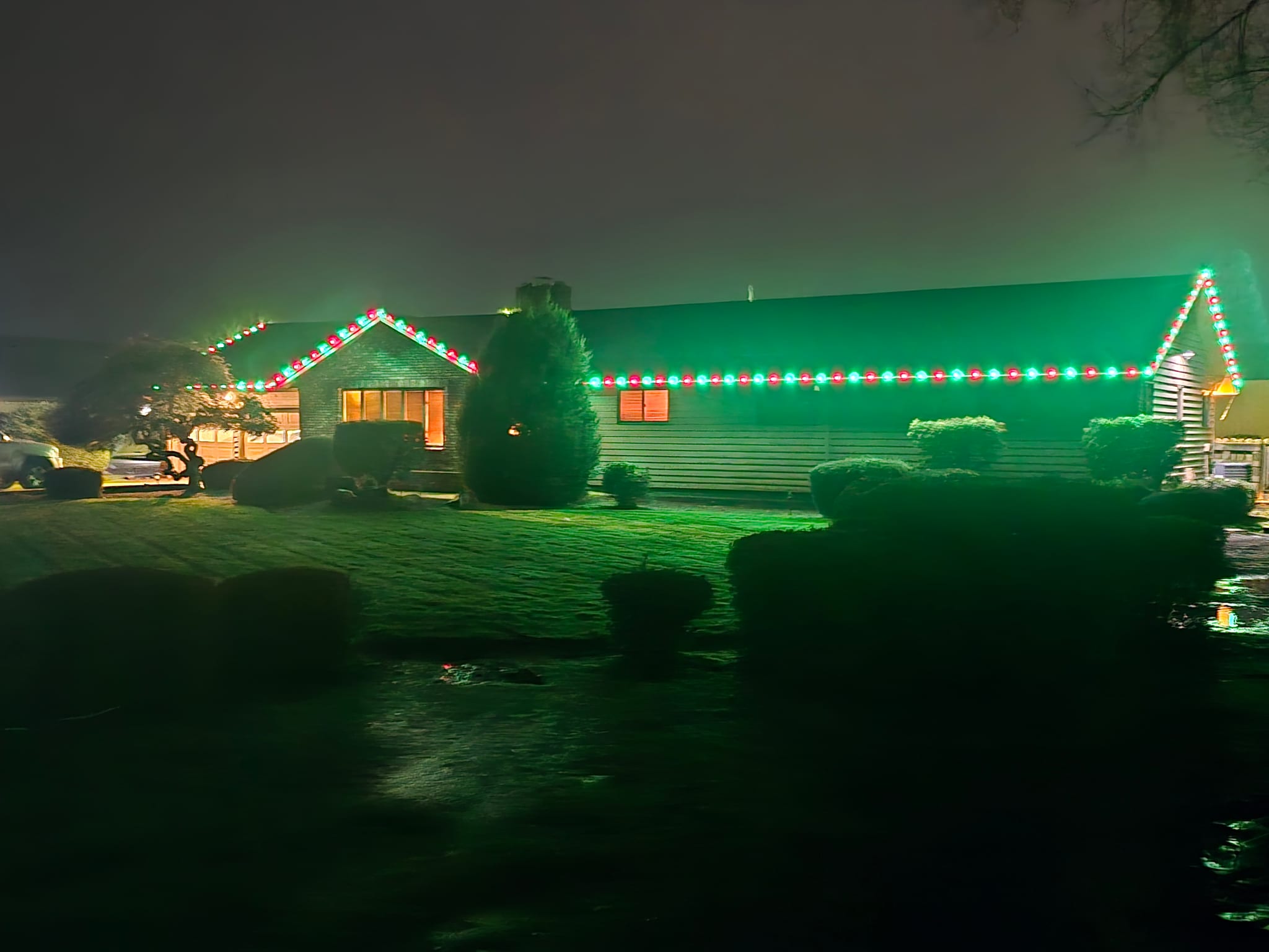 Single-storey ranch home with alternating red and green C9 Christmas lights along the roofline and gables