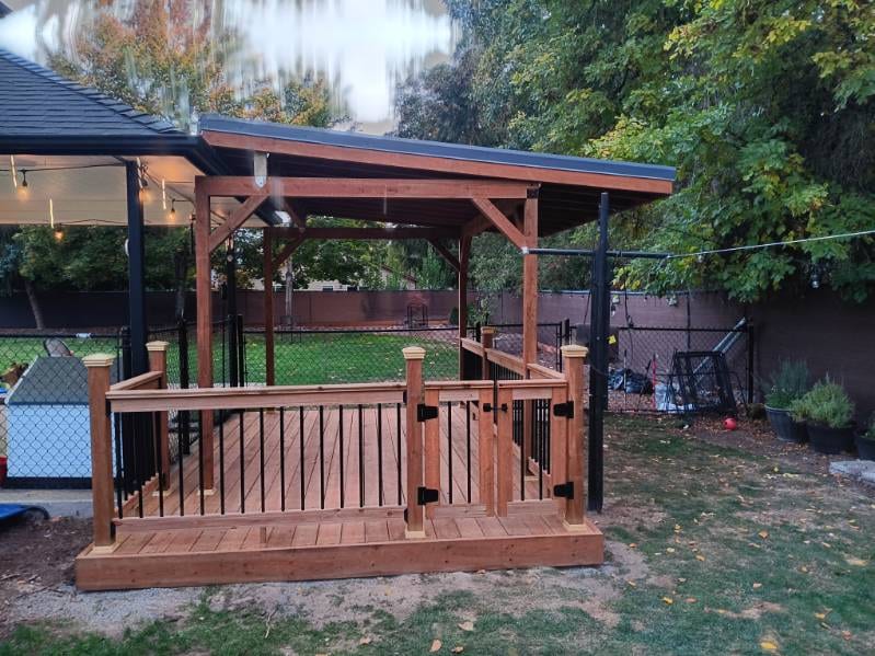 Covered backyard deck with a gated rail and black balusters, built by On Top Home Services and affiliates