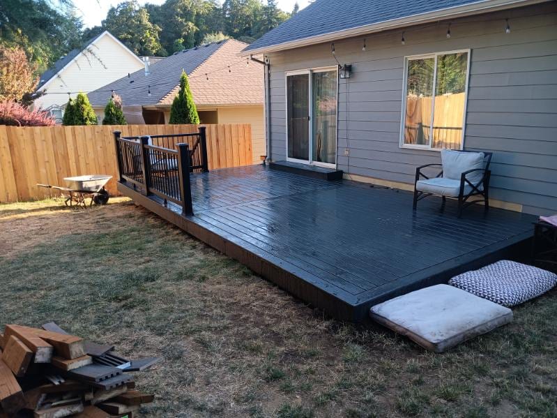 Dark-stained ground-level backyard deck against a cedar privacy fence, built by On Top Home Services and affiliates