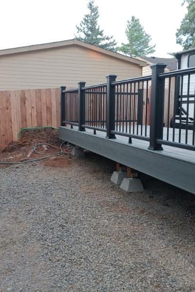 New cedar privacy fence beside a composite deck with a black aluminum railing, built by On Top Home Services and affiliates